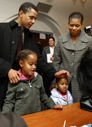 来自伊利诺伊州的民主党美国参议院候选人巴拉克奥巴马与妻子米歇尔、女儿马利斯（左）和萨沙与民意调查工作人员一起登记，以便他在天主教神学联盟排队投票投票站，星期二，2004 年 11 月 2 日，芝加哥。（美联社照片/Nam Y. Huh）