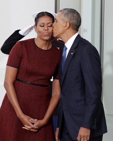 President Barack Obama kisses first lady Michelle Obama as they await for the arrival of President-elect Donald Trump and his wife Melania, Friday, Jan. 20, 2017, at the White House in Washington. (AP Photo/Evan Vucci)