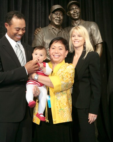 Tiger Woods, left, smiles as he stands with his daughter Sam, left to right, mother Kultida, and wife Elin Nordegren, next to a bronze statue bearing the likeness of Tiger with his late father Earl Woods, during its unveiling inside the the Tiger Woods Learning Center in Anaheim, Calif., Monday, Jan. 21, 2008. (AP Photo/Damian Dovarganes)