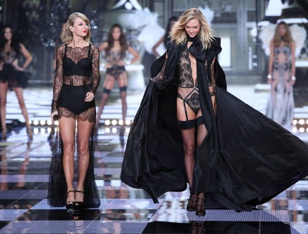 Model Karlie Kloss displays a creation alongside singer Taylor Swift, front left, at the Victoria's Secret fashion show in London, Tuesday, Dec. 2, 2014. (Photo by Joel Ryan/Invision/AP)