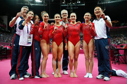 U.S. gymnasts, left to right wearing red, Gabrielle Douglas, McKayla Maroney, Alexandra Raisman, Jordyn Wieber and Kyla Ross celebrate with coaches Jenny Zhang, front left, Mihai Brestyan, back left, John Geddert, center, and Liang Chow, right, after their team won the gold medal for the Artistic Gymnastics women's team final at the 2012 Summer Olympics, Tuesday, July 31, 2012, in London. (AP Photo/Matt Dunham)