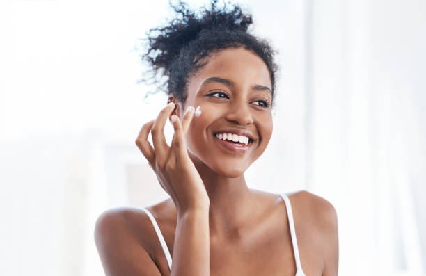 Shot of a young woman applying moisturizer to her face in the bathroom