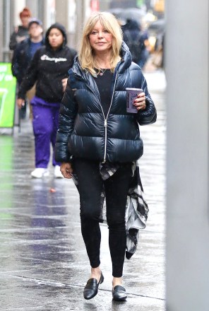 New York City, NY - *ÖZEL* - Goldie Hawn, Manhattan'ın Midtown bölgesinde yağmurlu bir sabahta elinde mor bir protein içeceği ve şık bir şişme ceket giyerken ördek görünümlü komik bir yüz hareketi yapıyor.  Resimde: Goldie Hawn BACKGRID ABD 17 ŞUBAT 2023 MUTLAKA OKUYUN: BrosNYC / BACKGRID ABD: +1 310 798 9111 / usasales@backgrid.com Birleşik Krallık: +44 208 344 2007 / uksales@backgrid.com *İngiltere Müşterileri - Çocuk İçeren Resimler Lütfen Yayınlanmadan Önce Yüzü Pikselleştirin*