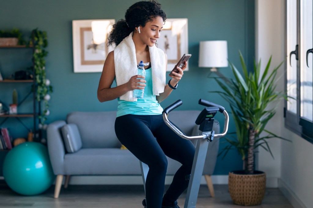 Shot of a young woman training on an exercise bike at home.