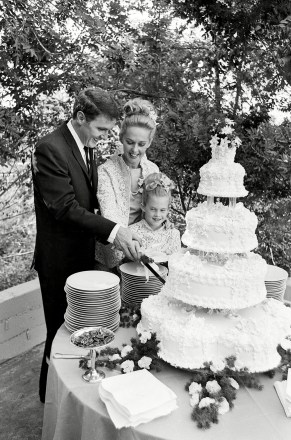 Aktris Tippi Hedren dan suaminya, manajer Noel Marshall, terlihat saat mereka memotong kue pernikahan dengan bantuan putri Hedren yang berusia tujuh tahun, Melanie, pada resepsi pernikahan mereka, yang diadakan di taman rumah pengantin wanita di Hollywood, California, di NEWLYWEDREN HEDREN MARSHALL, HOLLYWOOD, AS