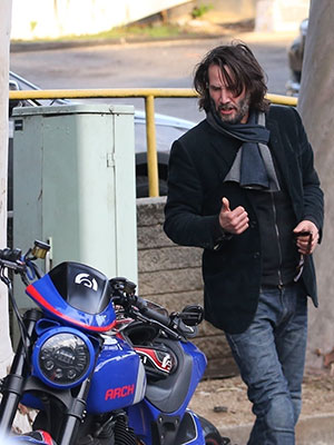 Keanu Reeves wears all black with a scruffy beard outside a New York City  hotel