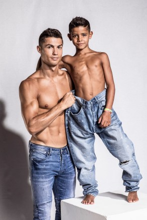 Cristiano Ronaldo and his mini-me are two peas in a pod in this very cute photoshoot for the football star’s new CR7 Junior denim line. The 32-year-old Real Madrid player and his seven-year-old son, Cristiano Ronaldo Jr, pose up a storm, flexing their muscles while shirtless and donning matching outfits. The CR7 Junior collection is available exclusively on CR7.com and markets itself as the “future of denim” with “unrivaled mobility”. Speaking about the new line, Ronaldo explained: “For me, the CR7 Junior collection is all about having fun and being free, being creative and confident. “The stretch denim we have used in the collection is extremely comfortable due to the technical elements in the fabric, which will allow boys to run around and be active, move freely and most importantly, play.” Ronaldo — who is also father to four-month-old twins Mateo and Eva Maria and whose girlfriend Georgina Rodriguez is pregnant with his fourth child — went on: “This is why we have used the PRESS PLAY tagline for the brand. “I believe the youth of today are the ones driving the society forward in so many ways and I felt that creating a denim collection with my son would celebrate this.”. 14 Nov 2017 Pictured: Cristiano Ronaldo and his son Cristiano Ronaldo Jr. pose together in a photoshoot for the Real Madrid star's new CR7 Junior denim line. Photo credit: CR7/ MEGA TheMegaAgency.com +1 888 505 6342 (Mega Agency TagID: MEGA116703_002.jpg) [Photo via Mega Agency]