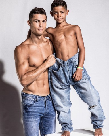 Cristiano Ronaldo and his mini-me are two peas in a pod in this very cute photoshoot for the football star’s new CR7 Junior denim line. The 32-year-old Real Madrid player and his seven-year-old son, Cristiano Ronaldo Jr, pose up a storm, flexing their muscles while shirtless and donning matching outfits. The CR7 Junior collection is available exclusively on CR7.com and markets itself as the “future of denim” with “unrivaled mobility”. Speaking about the new line, Ronaldo explained: “For me, the CR7 Junior collection is all about having fun and being free, being creative and confident. “The stretch denim we have used in the collection is extremely comfortable due to the technical elements in the fabric, which will allow boys to run around and be active, move freely and most importantly, play.” Ronaldo — who is also father to four-month-old twins Mateo and Eva Maria and whose girlfriend Georgina Rodriguez is pregnant with his fourth child — went on: “This is why we have used the PRESS PLAY tagline for the brand. “I believe the youth of today are the ones driving the society forward in so many ways and I felt that creating a denim collection with my son would celebrate this.”. 14 Nov 2017 Pictured: Cristiano Ronaldo and his son Cristiano Ronaldo Jr. pose together in a photoshoot for the Real Madrid star's new CR7 Junior denim line. Photo credit: CR7/ MEGA TheMegaAgency.com +1 888 505 6342 (Mega Agency TagID: MEGA116703_002.jpg) [Photo via Mega Agency]