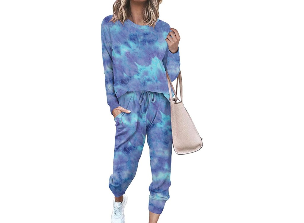 A woman wearing a blue tie-dye lounge set with a bag.