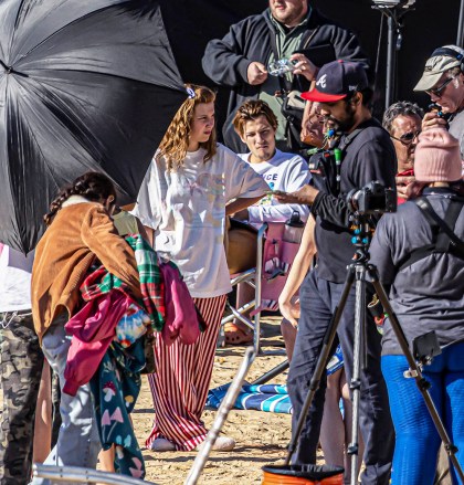 EXCLUSIVE: Jake Bongiovi keeps an eye on his girlfriend Millie Bobby Brown as she shoots The Electric State in Atlanta, Georgia.  The 18-year-old British actress wore baggy red and white pajama-style pants and slippers while filming a beach scene with her lover sitting directly behind her.2022 Oct. 26 Photo: Jake Bongiovi and Millie Bobby Brown. Photo credit: OG-MEGA TheMegaAgency.com +1 888 505 6342 (Mega Agency TagID: MEGA911550_040.jpg) [Photo via Mega Agency]