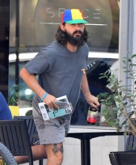 EXCLUSIVE: Shia LaBeouf holds a rosary in his hand as he reads a book about a Franciscan priest and saint. Shia was seen sitting on his own drinking a kombucha drink outside of a health food restaurant. He was seen clutching a rosary and reading the book "Padre Pio,'"as it seems he is getting ready for his next film role which is meant to be his come-back role. 23 Aug 2021 Pictured: Shia Labeouf. Photo credit: Snorlax / MEGA TheMegaAgency.com +1 888 505 6342 (Mega Agency TagID: MEGA780752_021.jpg) [Photo via Mega Agency]