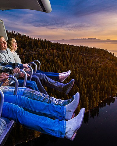 Aerial drone view perfect redwoods and sequoia and Jeffrey pines and Western Yellow Pines running along the shoreline of majestic Lake Tahoe at sunrise looking down on trees and waters edge with Sierra Nevada Mountains in background