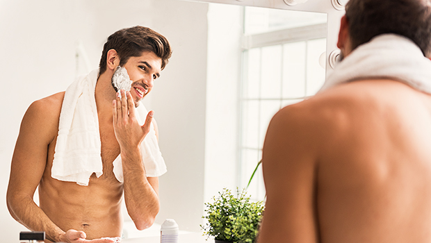 A man applies shaving cream after a shower.