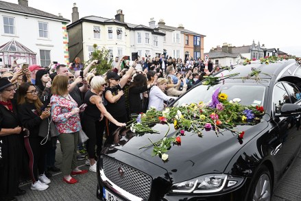 Fans gather for a 'last goodbye' to the Irish singer Sinead O'Connor as her hearse passes by her former home in Bray, Co Wicklow, Ireland, 08 August 2023. The funeral cortege passed by her old home on the way to the private burial service for the 56-years old singer, who was found dead at her home in London on 26 July 2023.
Fans gather to watch procession of Sinead O'Connor, Bray, Ireland - 08 Aug 2023