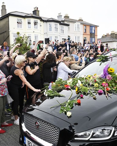 Fans gather for a 'last goodbye' to the Irish singer Sinead O'Connor as her hearse passes by her former home in Bray, Co Wicklow, Ireland, 08 August 2023. The funeral cortege passed by her old home on the way to the private burial service for the 56-years old singer, who was found dead at her home in London on 26 July 2023.
Fans gather to watch procession of Sinead O'Connor, Bray, Ireland - 08 Aug 2023