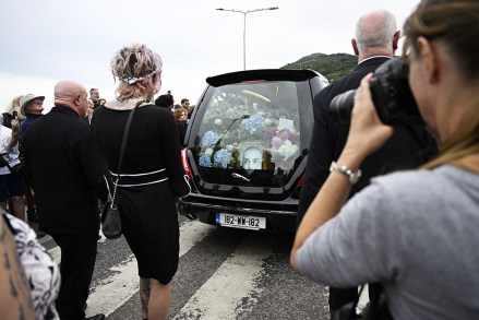 Fans gather for a 'last goodbye' to the Irish singer Sinead O'Connor as her hearse passes by her former home in Bray, Co Wicklow, Ireland, 08 August 2023. The funeral cortege passed by her old home on the way to the private burial service for the 56-years old singer, who was found dead at her home in London on 26 July 2023.
Fans gather to watch procession of Sinead O'Connor, Bray, Ireland - 08 Aug 2023