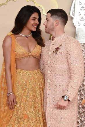 Indian actress Priyanka Chopra Jonas (L) and her husband American singer-songwriter and actor Nick Jonas (R) pose for photos as they arrive to attend the wedding ceremony of billionaire tycoon and Chairman of Reliance Industries Mukesh Ambani's son Anant Ambani and Radhika Merchant in Mumbai on July 12, 2024. Socialite sisters Kim and Khloe Kardashian were among the global celebrities spotted in India on July 12 to attend a lavish three-day wedding ceremony staged by Asia's richest man Mukesh Ambani. (Photo by SUJIT JAISWAL / AFP) (Photo by SUJIT JAISWAL/AFP via Getty Images)