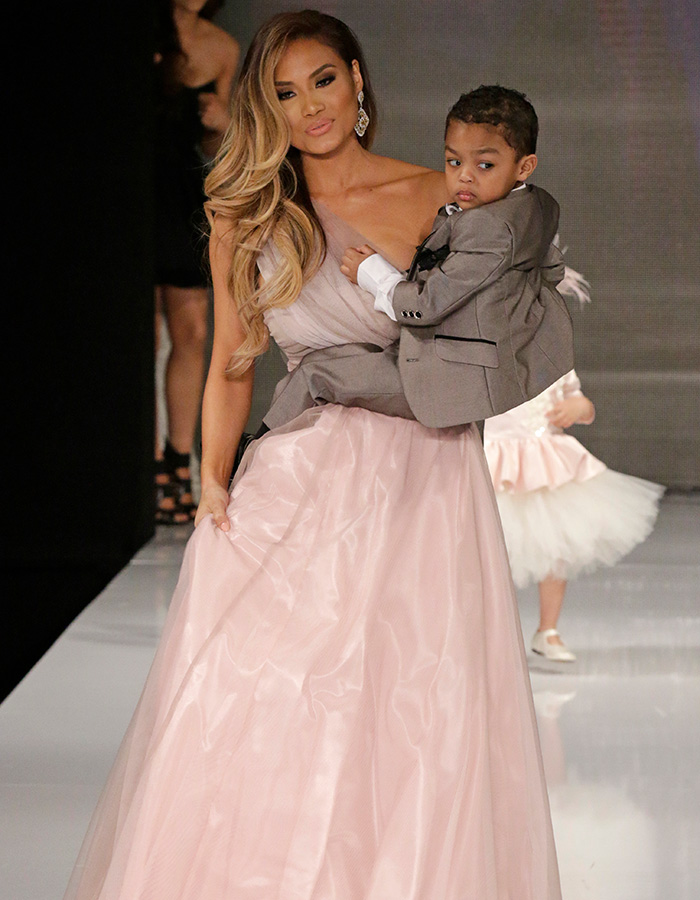 Daphne Joy con un vestido rosa cargando a su hijo Sire 