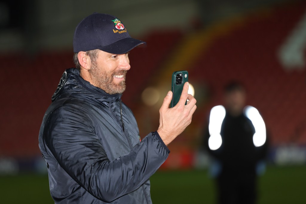 WREXHAM, WALES - APRIL 22: Wrexham co-owners Ryan Reynolds FaceTimes his wife Blake Lively as Wrexham celebrate promotion back to the English Football League during the Vanarama National League match between Wrexham and Boreham Wood at Racecourse Ground on April 22, 2023 in Wrexham, Wales. (Photo by Matthew Ashton - AMA/Getty Images)