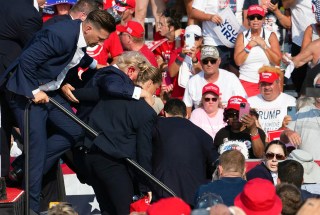 Republican candidate Donald Trump is seen with blood on his face surrounded by secret service agents as he is taken off the stage at a campaign event at Butler Farm Show Inc. in Butler, Pennsylvania, July 13, 2024. Republican candidate Donald Trump was evacuated from the stage at today's rally after what sounded like shots rang out at the event in Pennsylvania, according to AFP.The former US president was seen with blood on his right ear as he was surrounded by security agents, who hustled him off the stage as he pumped his first to the crowd.Trump was bundled into an SUV and driven away. (Photo by Rebecca DROKE / AFP) (Photo by REBECCA DROKE/AFP via Getty Images)