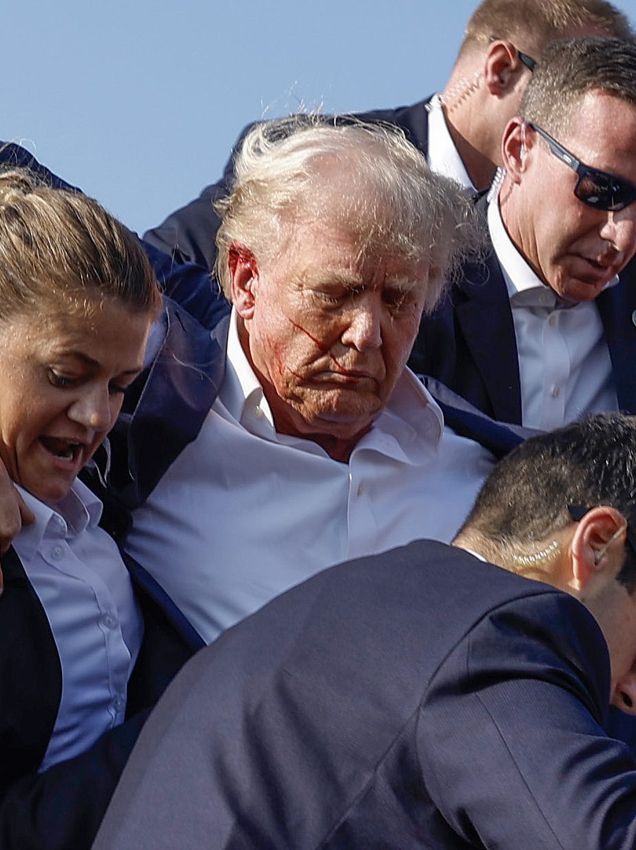 BUTLER, PENNSYLVANIA - JULY 13: Republican presidential candidate former President Donald Trump is rushed offstage by U.S. Secret Service agents after being grazed by a bullet during a rally on July 13, 2024 in Butler, Pennsylvania. Butler County district attorney Richard Goldinger said the shooter is dead after injuring former U.S. President Donald Trump, killing one audience member and injuring another in the shooting. (Photo by Anna Moneymaker/Getty Images)