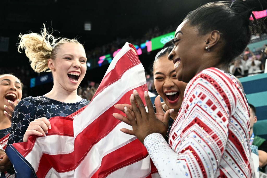 US' Simone Biles (R) and teammates celebrate after team USA won the artistic gymnastics women's team final during the Paris 2024 Olympic Games at the Bercy Arena in Paris, on July 30, 2024. (Photo by Lionel BONAVENTURE / AFP) (Photo by LIONEL BONAVENTURE/AFP via Getty Images)