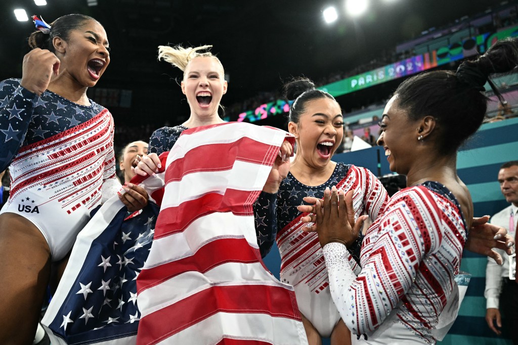 TOPSHOT - US' Simone Biles (R) and teammates celebrate after team USA won the artistic gymnastics women's team final during the Paris 2024 Olympic Games at the Bercy Arena in Paris, on July 30, 2024. (Photo by Lionel BONAVENTURE / AFP) (Photo by LIONEL BONAVENTURE/AFP via Getty Images)