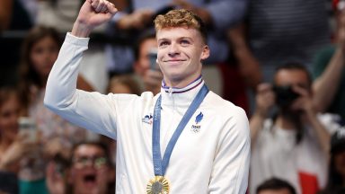 Leon Marchand of Team France celebrates on the podium after victory in the Men's 400m IM final on day two of the Olympic Games Paris 2024 at Paris La Defense Arena on July 28, 2024 in Nanterre, France. (Photo by Ian MacNicol/Getty Images)