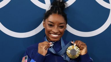 PARIS, FRANCE - AUGUST 01: (EDITOR'S NOTE: Alternate crop) Gold medalist Simone Biles of Team United States poses with the Olympic Rings and a goat charm on her necklace during the Artistic Gymnastics Women's All-Around Final medal ceremony on day six of the Olympic Games Paris 2024 at Bercy Arena on August 01, 2024 in Paris, France. (Photo by Jamie Squire/Getty Images)