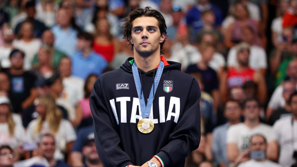 Thomas Ceccon of Team Italy stands on the podium during the Swimming medal ceremony