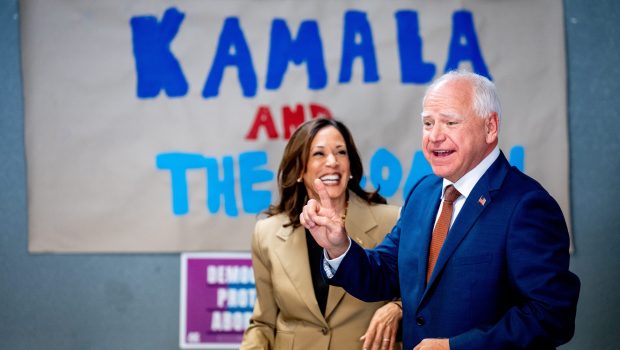 GLENDALE, ARIZONA - AUGUST 9: Democratic vice presidential candidate Minnesota Governor Tim Walz asks Democratic presidential candidate, U.S. Vice President Kamala Harris for a selfie in front of a sign that reads "Kamala and The Coach" during stop at a campaign office on August 9, 2024 in Glendale, Arizona. Kamala Harris and her newly selected running mate Tim Walz are campaigning across the country this week. (Photo by Andrew Harnik/Getty Images)