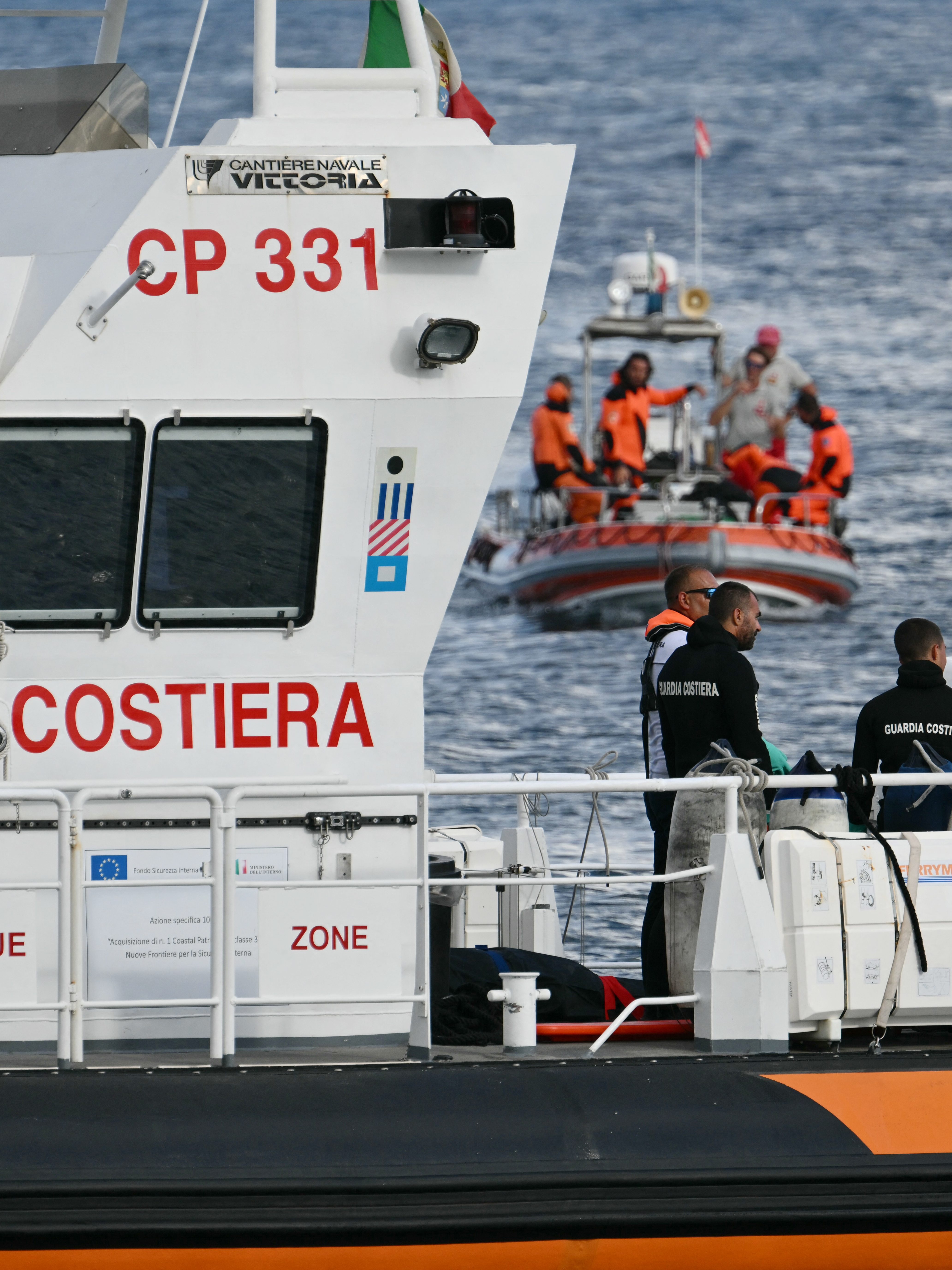 Italian Coast Guards carry a body on a rescue boat in Porticello harbor near Palermo, with a third body at the back of the boat on August 21, 2024, two days after the British-flagged luxury yacht Bayesian sank. Divers searching for six missing people following the sinking of a superyacht off Sicily in a storm have found four bodies, a source close to the search told AFP. The Bayesian, which had 22 people aboard including 10 crew, was anchored some 700 metres from port before dawn when it was struck by a waterspout. Among the six missing were UK tech entrepreneur Mike Lynch and his 18-year-old daughter Hannah, and Jonathan Bloomer, the chair of Morgan Stanley International, and his wife Judy. (Photo by Alberto PIZZOLI / AFP) (Photo by ALBERTO PIZZOLI/AFP via Getty Images)