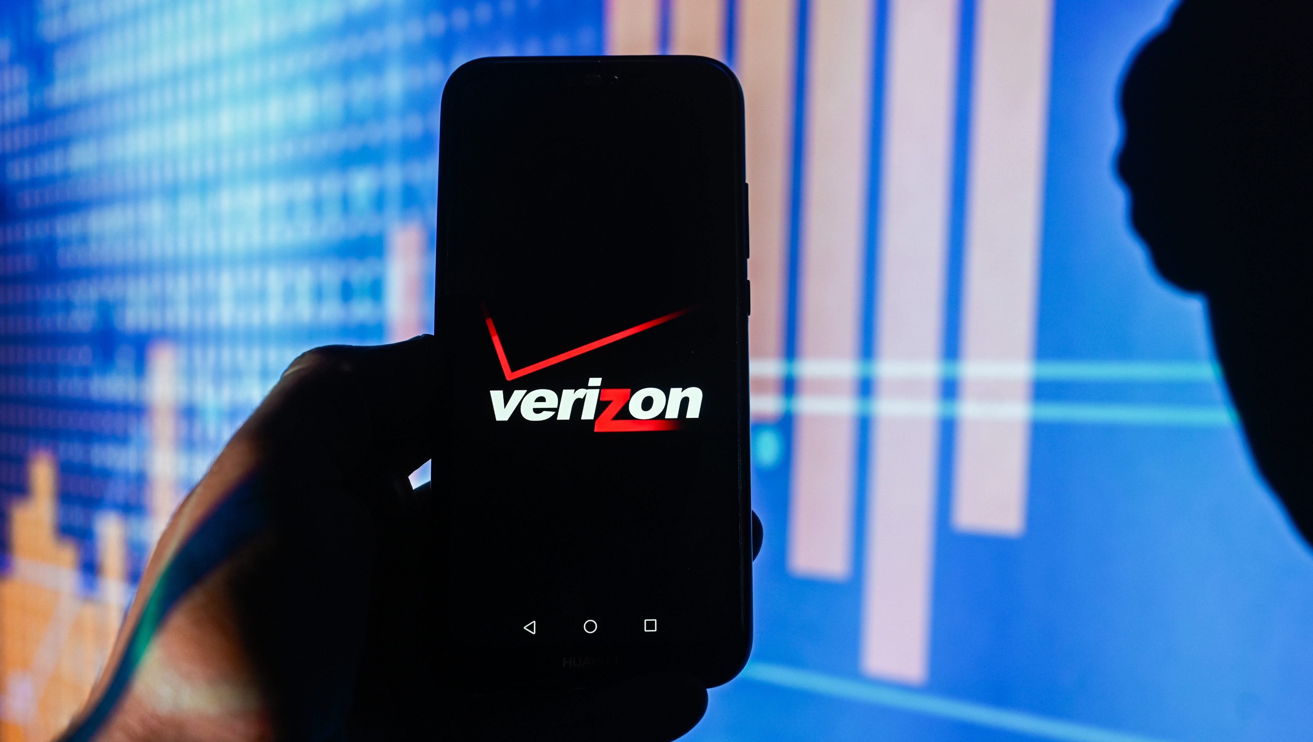 A Verizon logo is displayed on a smartphone with stock market percentages in the background. (Photo Illustration by Omar Marques/SOPA Images/LightRocket via Getty Images)