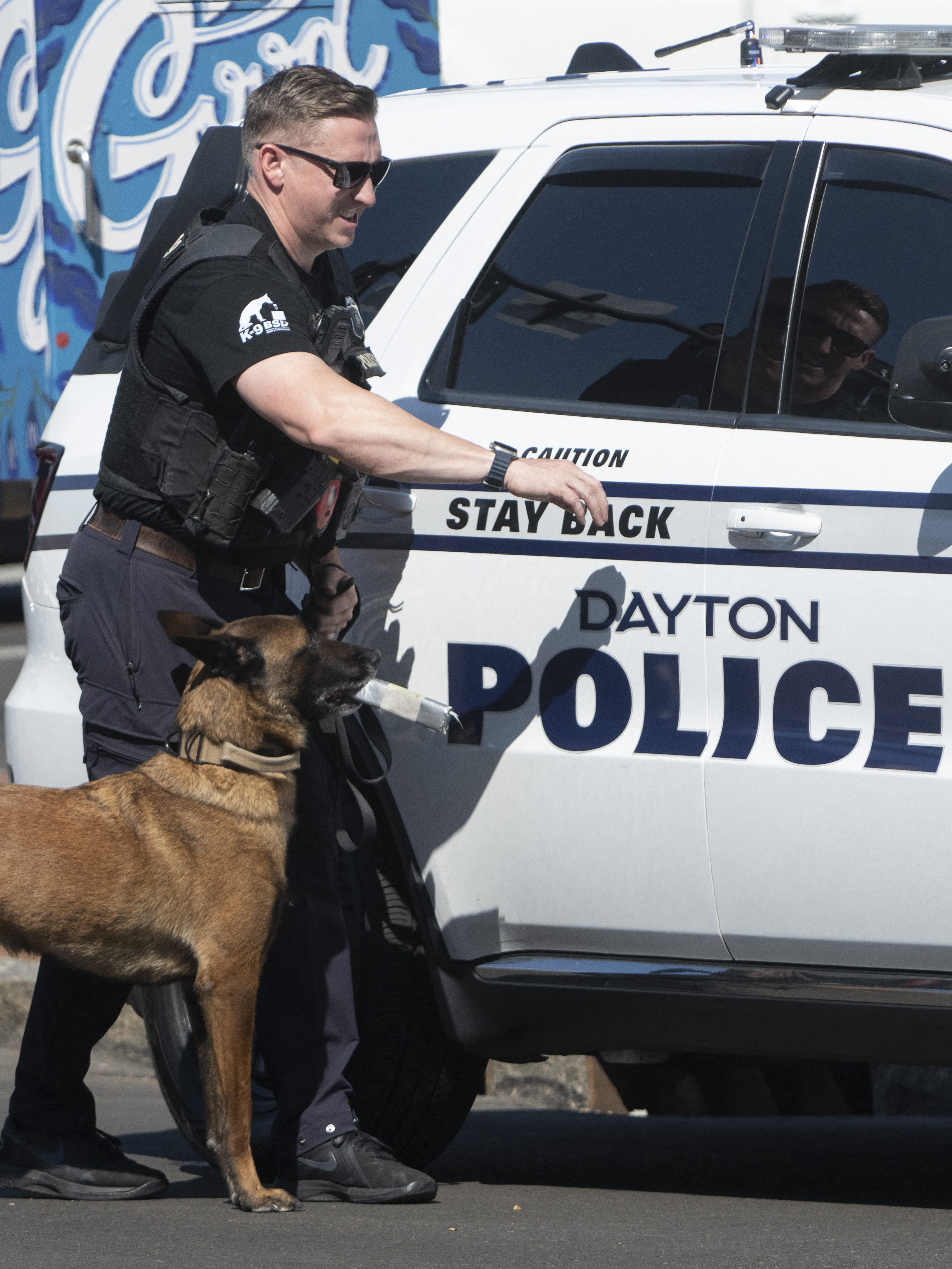 A Dayton police officer and his dog return to their vehicle after sweeping the Springfield City Hall grounds for explosives after bomb threats were made against buildings earlier in the day in Springfield, Ohio on September 12, 2024. A government building and school were evacuated after an alleged bomb threat Thursday in Springfield, Ohio, local media reported, rattling the small city at the heart of an anti-migrant conspiracy theory amplified by Donald Trump. Springfield has been thrust into the spotlight in recent days after an unfounded story of Haitian migrants eating pets went viral on social media, with the Republican ex-president and current White House candidate pushing the narrative despite it being debunked. (Photo by ROBERTO SCHMIDT / AFP) (Photo by ROBERTO SCHMIDT/AFP via Getty Images)