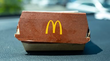 Zbliżenie na opakowanie burgera McDonald's z logo widocznym na desce rozdzielczej samochodu, San Ramon, Kalifornia, 3 sierpnia 2024 r. (Zdjęcie: Smith Collection/Gado/Getty Images)