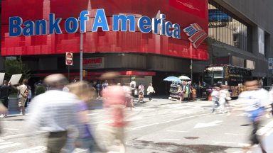  People and tourist walking by the colorful electronic sign of Bank of America. The sign is one of many colorful signs in Times Square.