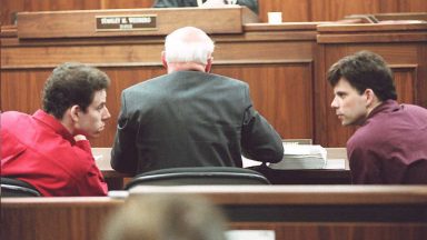 LOS ANGELES, UNITED STATES: Erik (L) and Lyle (R) Menendez converse in the courtroom during a hearing in Los Angeles, in this 02 February 1995 file picture. They are accused of murdering their parents in 1989. (Photo credit should read KIM KULISH/AFP via Getty Images)