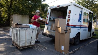  Postman Robert Nagel loads packages onto a mail truck outside the post office in Winterville, Georgia.(Dustin Chambers for The Washington Post via Getty Images)