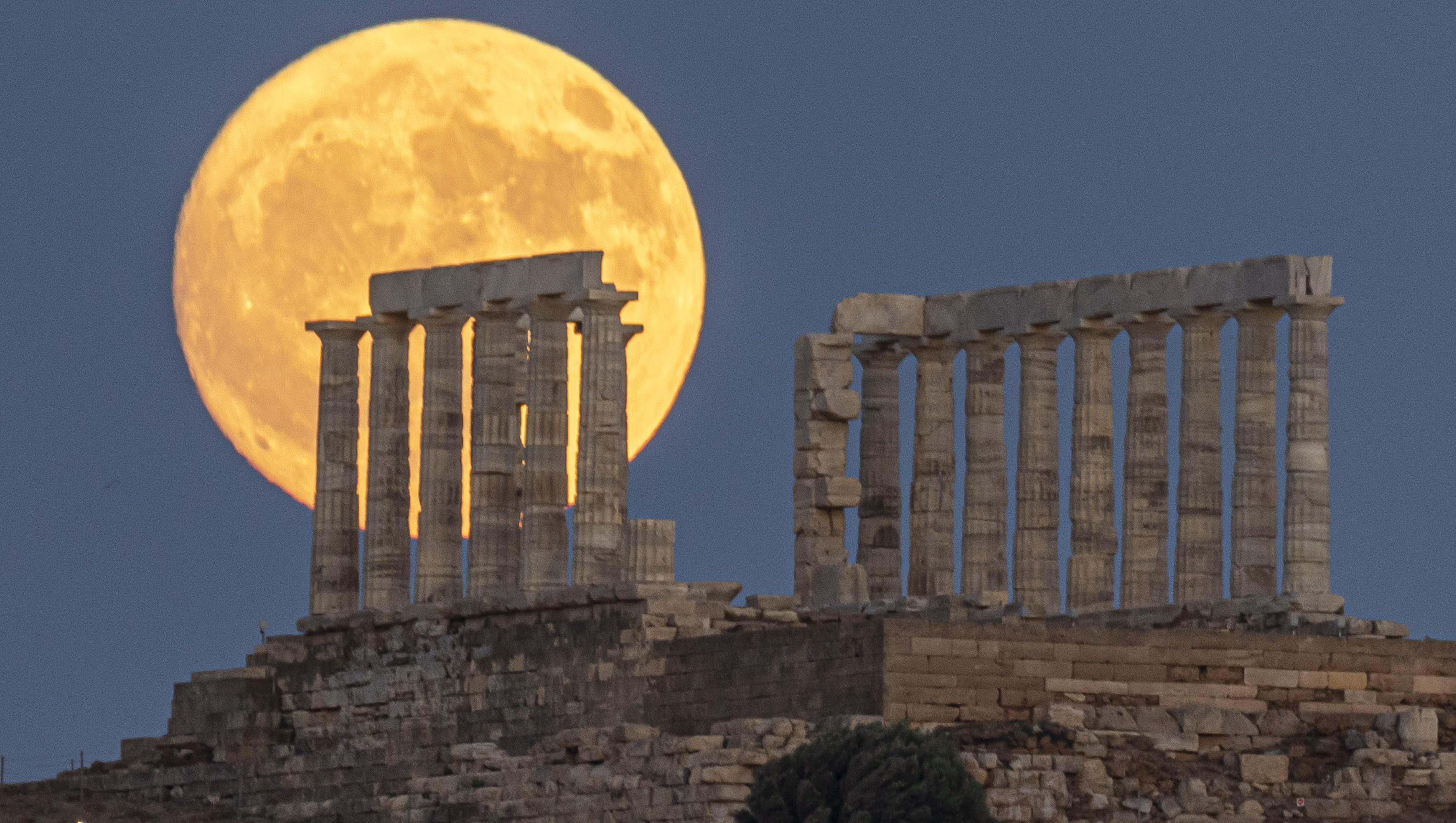 The Full Buck Moon rises behind the ancient Greek Temple of Poseidon on Cape Sounion in Greece on July 20, 2024 (Photo by Nicolas Economou/NurPhoto via Getty Images)