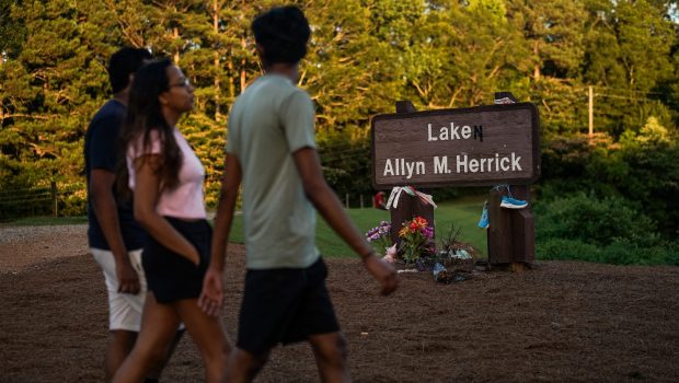 People pass by a memorial to Laken Riley at Lake Allyn Herrick on the campus of the University of Georgia on June 7, 2024, in Athens, Georgia. On February 22, 2024, Riley, a nursing student at Augusta University, was killed while she was jogging at the University of Georgia in Athens, Georgia. Her body was found in Oconee Forest Park near the lake. The suspect, José Antonio Ibarra, a 26-year-old Venezuelan, had reportedly entered the US illegally. (Photo by Elijah Nouvelage / AFP)