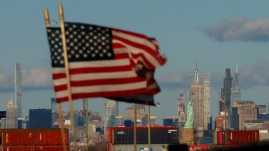 BAYONNE, NJ - FEBRUARY 1: Shipping containers stand on a dock at the Port Jersey container terminal in front of the Statue of Liberty and the Empire State Building in New York City on February 1, 2025, as seen from Bayonne, New Jersey.  (Photo by Gary Hershorn/Getty Images)